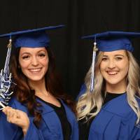 two women wave pom poms around at GradFest